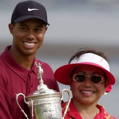Kultida Woods holding the golf championship trophy with his son Tiger Woods.